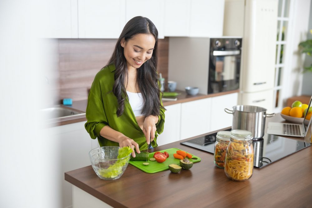 person cutting vegetables on plastic board